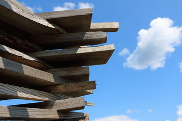 Ends of the rough pine boards in the outdoor stack against a blue sky