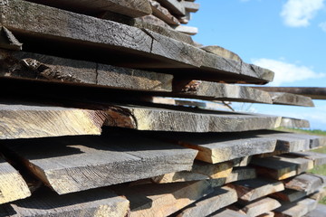 Ends of the rough pine boards in the outdoor stack against a blue sky