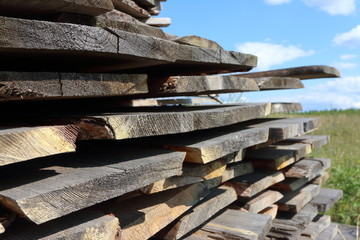 Ends of the rough pine boards in the outdoor stack against a blue sky