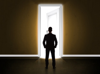 Obraz premium Business man looking at big bright opened door