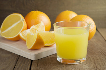 glass of orange juice and oranges on the wooden table