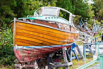 Fototapeta na wymiar A beautiful old wooden boat is up on land for repairs in a dry dock. Location: Sweden. 
