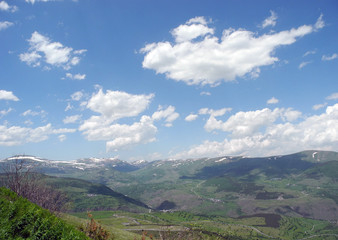Obraz premium Snow-covered peaks and small clouds in the sky.