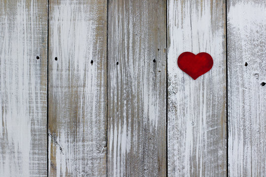 Red heart hanging on whitewash rustic fence