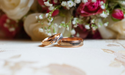 Wedding gold rings on a background of red roses