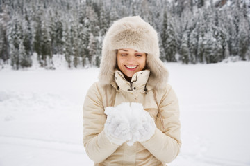Obraz premium Woman looking on snow in hands while standing outdoors