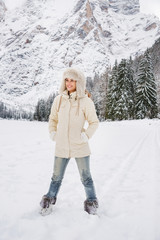 Fototapeta na wymiar Woman in white coat and fur hat standing in winter outdoors