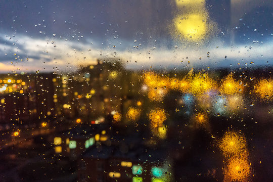 Window with drops of night rain in a city