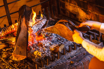 Closeup hands fireplace making fire with bellows.