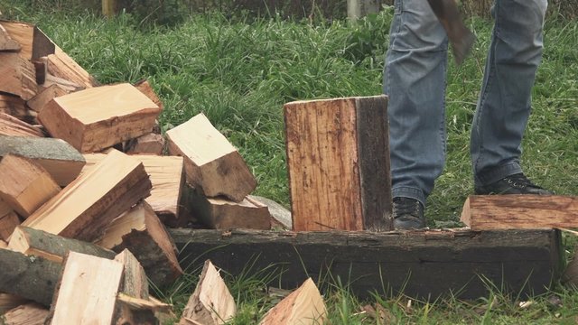 Male lumberjack chopping firewood with axe in backyard