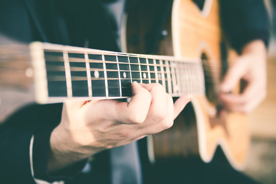 Young Man Casual Dressed  Playing Guitar. Music, Instrument Education And Learning Concept. Warm Soft Faded Vintage Post Processed 