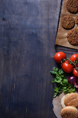 Grilled ground beef meat Burger steak cutlets with seasoning, tomatoes, parsley and bun on vintage wooden board, space for text.