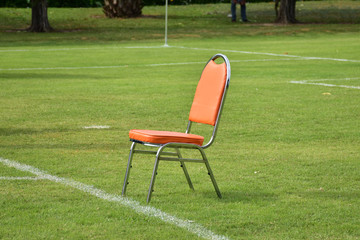 Obraz na płótnie Canvas orange chair on green field