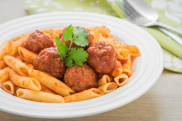 Penne pasta with meatballs in tomato sauce on plate