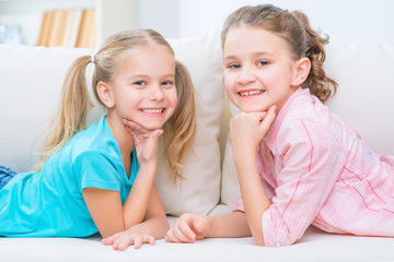 Cheerful little sisters sitting on the sofa 