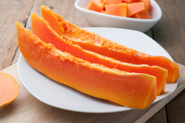 Sliced papaya on white plates and wooden background.