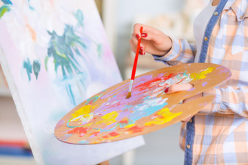 Young girl is busy oil-painting. 