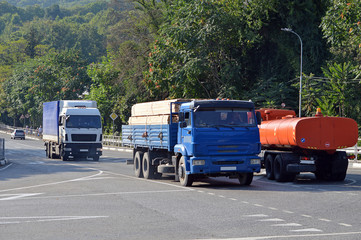 Большегрузные автомобили-грузовики движутся по улице маленького южного города