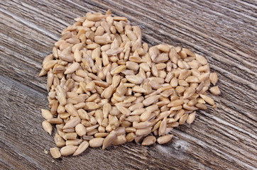 Heart of sunflower seeds on wooden background