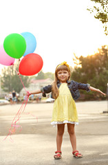 Little girl with balloons outside