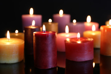 Many burning small candles on dark background, close-up