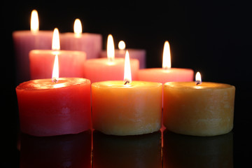 Many burning small candles on dark background, close-up