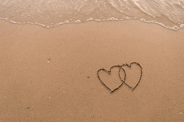 Fototapeta na wymiar two hearts drawn in beach