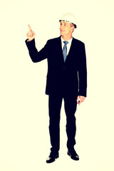 Smiling businessman with hard hat pointing up