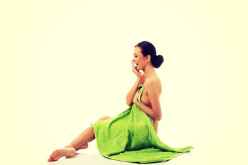 Laughing woman sitting wrapped in towel 