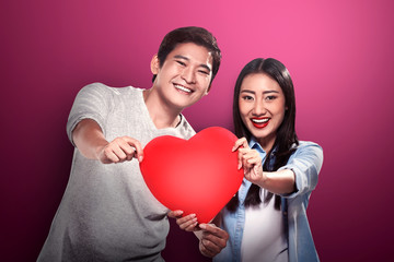 Portrait of man and woman holding red heart