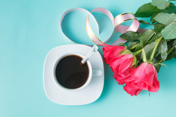 Cup of coffee and red roses on aquamarine background
