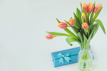Bouquet of tulip flowers in the vase and gift on the white background