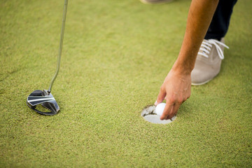 Golf ball, putter and boy's legs on green