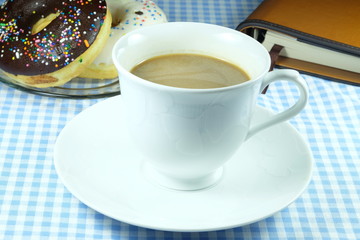 Coffee in white mug and note book and donuts