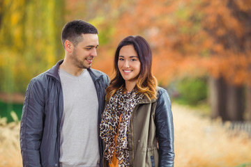 Fototapeta premium Happy young man looking at his beautiful girlfriend while walking through the park
