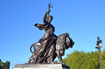 Bronze lion and monumental figure (Peace) at the Victoria Memorial in London, UK. Located at the...