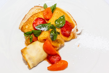 Pancakes sprinkled with powdered sugar fruit and berries are on