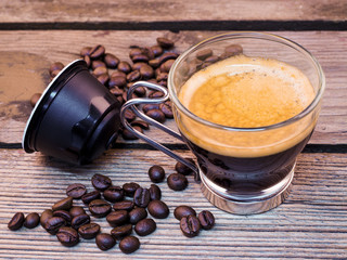 Cup of coffee and pods on wooden table