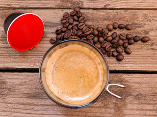 Cup of coffee and pods on wooden table
