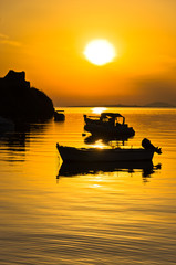 Naklejka na ściany i meble Boat on a calm sea at sunset in Toroni bay, Sithonia, Greece