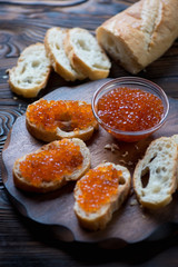 Salmon red caviar in a glass bowl and sandwiches, close-up