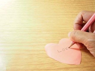 Fototapeta premium Writing, love word on pink sticky paper note by pencil