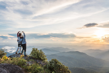 Young happy tourist on top of a mountain enjoying valley view