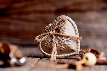 Silver heart on a wooden table with decorations. Valentines day. Love. Gift on a natural background. 