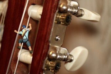 miniature di alpinisti mentre scalano una chitarra classica