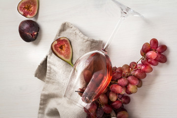 wineglass with rose wine and grapes on white wood textured table covered with canvas towel
