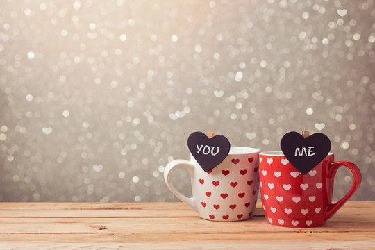 Valentine's day holiday celebration with couple of cups and hearts over bokeh background