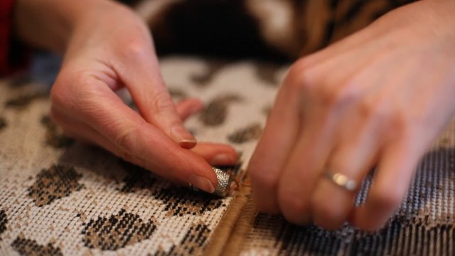 Particolari mani di donna che cuciono tappeto