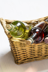 Obraz premium three bottles of white, rose and red whine in wicker basket