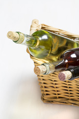 three bottles of white, rose and red whine in wicker basket